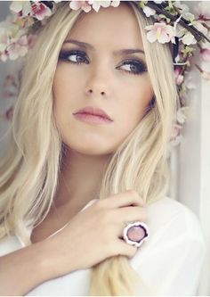 a woman wearing a flower crown with long blonde hair and blue eyeshade is posing for the camera