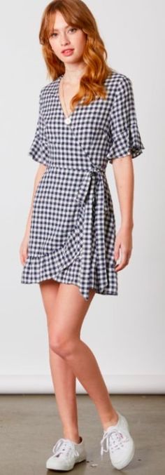 Navy Gingham Wrap Dress. Relaxing on the front porch sipping on a tall glass of lemonade in the Courtney Navy and White Gingham Wrap Dress! Lightweight woven fabric, in a navy and white checkered print, forms a surplice bodice with short flounce sleeves. Tying, ruffled wrap skirt (with hidden internal button) falls to a cute mini length. Short Sleeve Gingham Plaid Dress For Brunch, Gingham Plaid V-neck Dress For Brunch, V-neck Gingham Plaid Dress For Picnic, Gingham Plaid V-neck Dress For Picnic, Gingham V-neck Dress For Vacation, Gingham V-neck Mini Dress For Picnic, Spring Gingham Plaid Dress With V-neck, Dress With Flounce, Fitted Gingham Plaid Dress V-neck