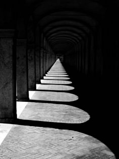 black and white photo of long walkways in an old building with light coming from the windows