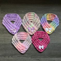 four crocheted baby bibs with bows on the sides and one has a bow at the end