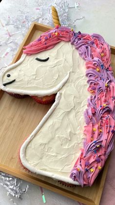 a cake shaped like an unicorn with pink frosting and sprinkles on it