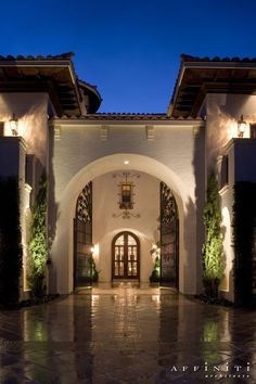 an entrance to a large home with lights on the front door and side entry way