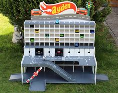 a toy model of a building with cars on it and a slide in the grass