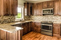 a kitchen with wooden cabinets and granite counter tops, stainless steel stove top oven and dishwasher