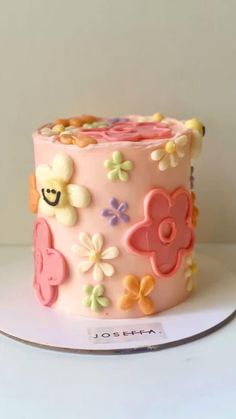 a close up of a cake on a plate with flowers and smiley face decorations in the middle