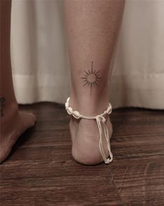 a woman's foot with a small sun tattoo on the left side of her ankle