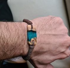 a man's arm with a bracelet made out of wood and turquoise glass beads