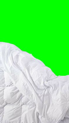 an unmade bed with white sheets and green screen in the backround against a green background