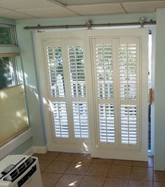 an empty room with white shutters on the doors and tile flooring in front of it