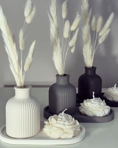 three black vases with white flowers in them