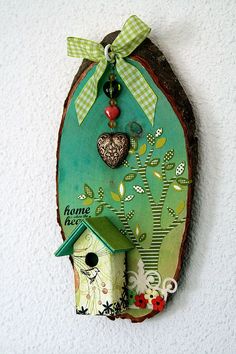 a green birdhouse with a heart hanging from it's side on a wall