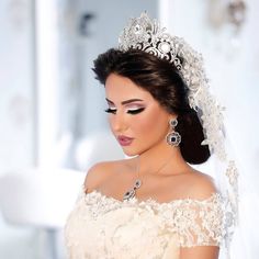 a woman in a wedding dress with a tiara on her head and veil over her shoulder