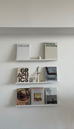 three white shelves with books on them against a wall