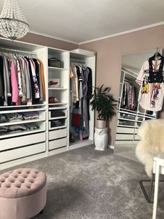 a walk in closet filled with clothes next to a white table and chair on top of carpeted floor