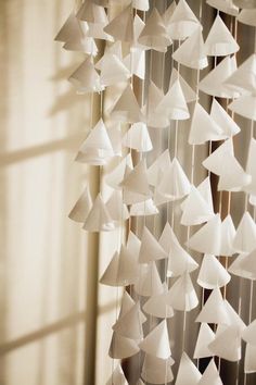 a wind chime made out of paper boats hanging from the side of a window