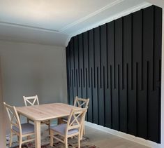 a dining room table and chairs in front of a wall with vertical black panels on it