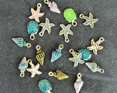 various sea shells and starfish charms on a gray surface, including one in the middle