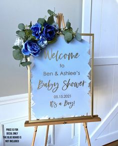 a welcome sign with blue flowers on it in front of a white wall and door