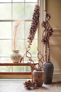 two vases with plants in them sitting on a window sill next to a bench