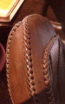 a pair of brown leather shoes with braiding on them next to a coffee cup