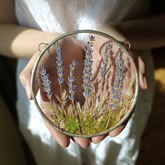 a person holding a small glass plate with lavenders on it and moss in the middle