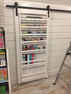 a ladder that is next to a shelf filled with paint and crafting supplies on it