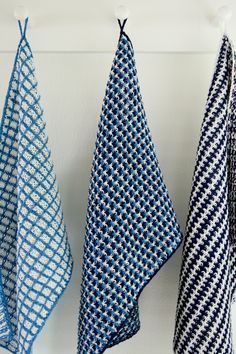 three blue and white towels hanging from hooks