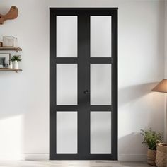 an empty room with a black door and shelves on the wall, next to a potted plant