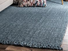 a blue rug with fringes on the floor in front of a couch and chair