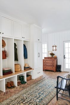 a room filled with lots of white cupboards and shelves next to a rug on top of a hard wood floor