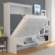 a white desk with a laptop on top of it and a large open bookcase