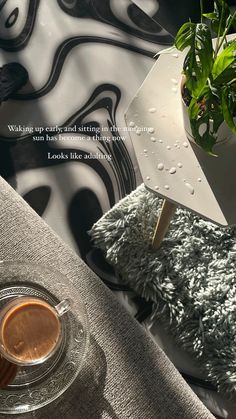 a cup of coffee sitting on top of a table next to a potted plant