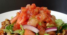 a white plate topped with lettuce, tomato and onion covered in ketchup