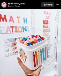 a person holding up a container with crayons on it