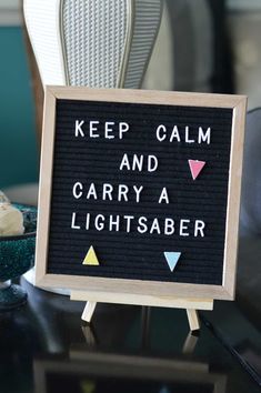 a sign that says keep calm and carry a light saber on top of a table