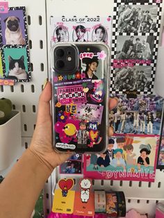 a person holding up a phone case with stickers on it