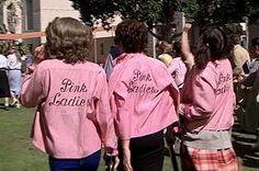 two girls in pink shirts are walking down the street with their hands up to the sky