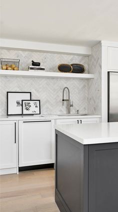 a kitchen with white cabinets and gray island