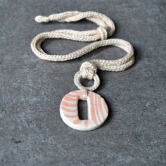 a white and pink necklace on a gray surface