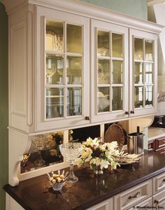 a kitchen with white cabinets and black counter tops, flowers in vases on the island