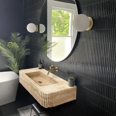 a bathroom with a sink and mirror next to a bathtub in front of a window