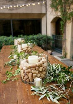 a wooden table topped with candles and greenery