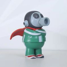 a green and black figurine with a red cape on it's head