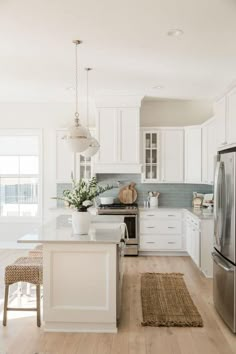 a kitchen with white cabinets and an island in the middle, along with stainless steel appliances