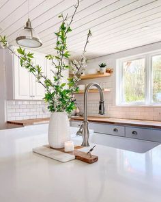 a kitchen with white cabinets and an island in the middle is decorated with greenery