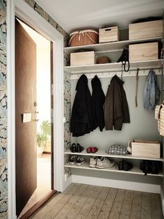 an open closet with shoes and coats hanging on the wall, next to a door