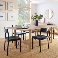 a dining room table with four chairs and a vase on top of it in front of a window