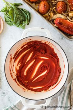 an overhead view of a sauce in a pot with vegetables and other food items around it