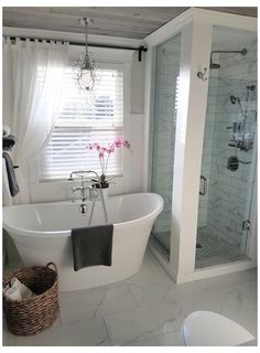 a white bath tub sitting under a window next to a toilet and shower stall in a bathroom