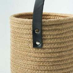 a large woven basket with leather handles on the bottom and black strap hanging from it's side